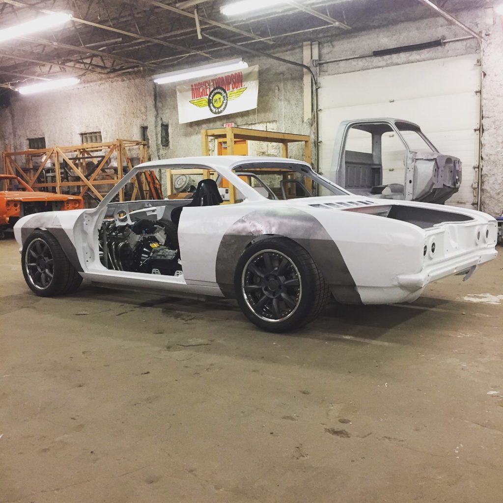 A white car is in the garage with its doors open.