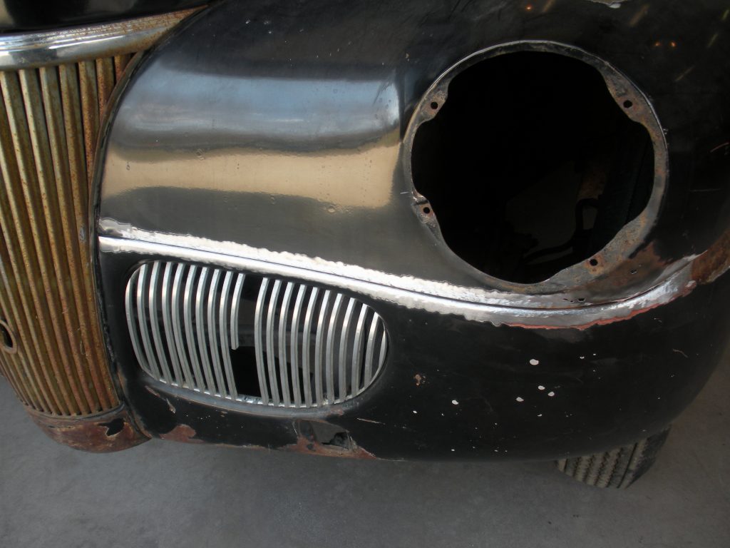 Here's an alt tag for the image: Rusty classic car front end repair.