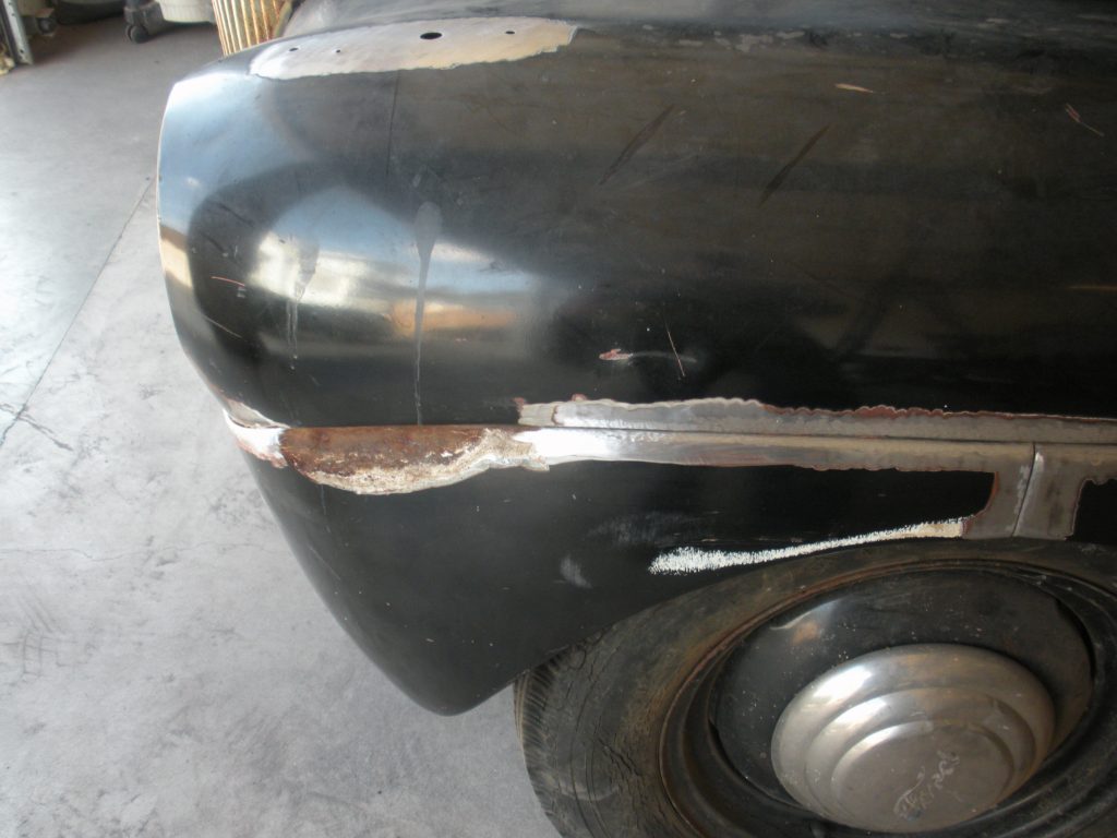 Black car fender with rust and weld.