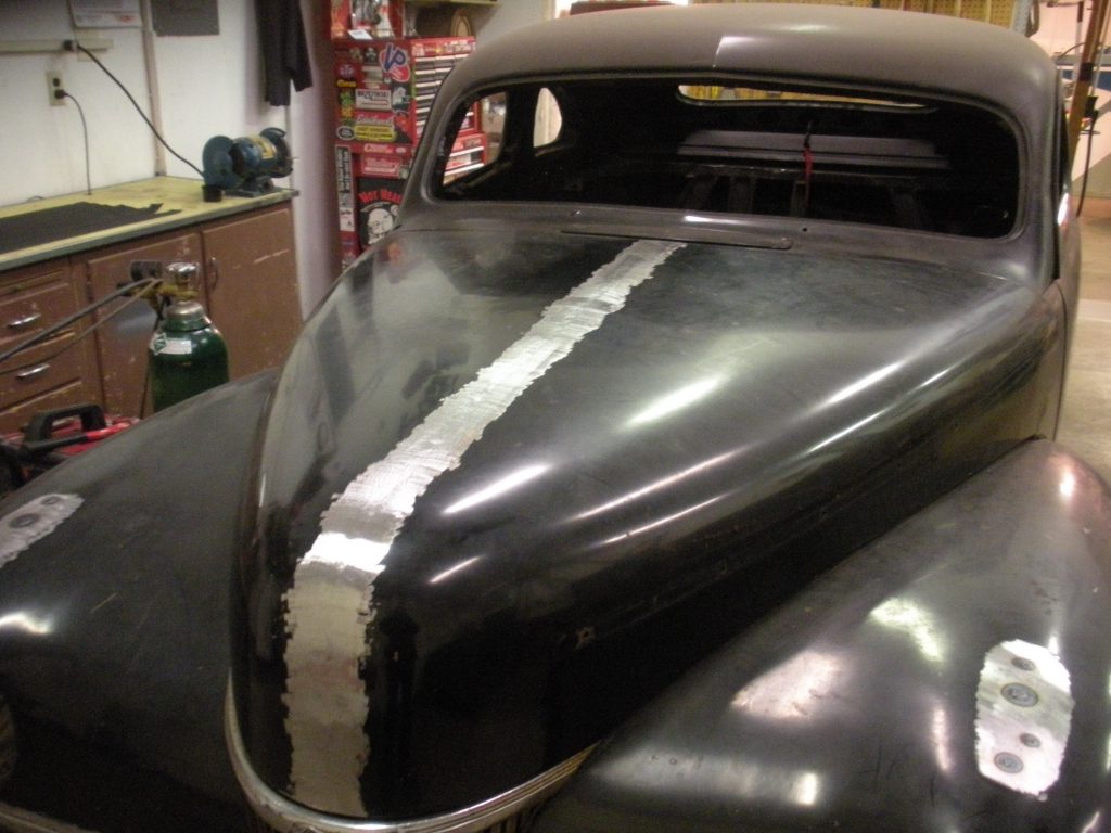 Black vintage car hood repair in progress.