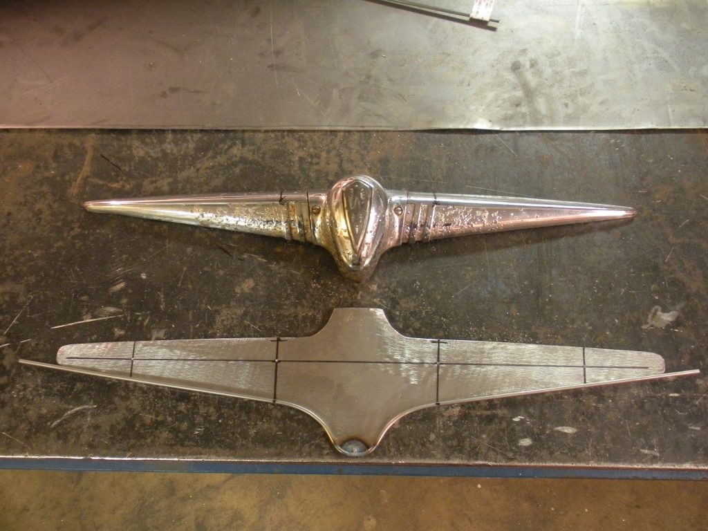 Here's an alt tag for the image: Chrome car hood ornament and metal template.