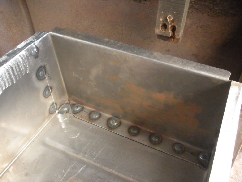 A metal box with holes in it and some rust on the bottom.