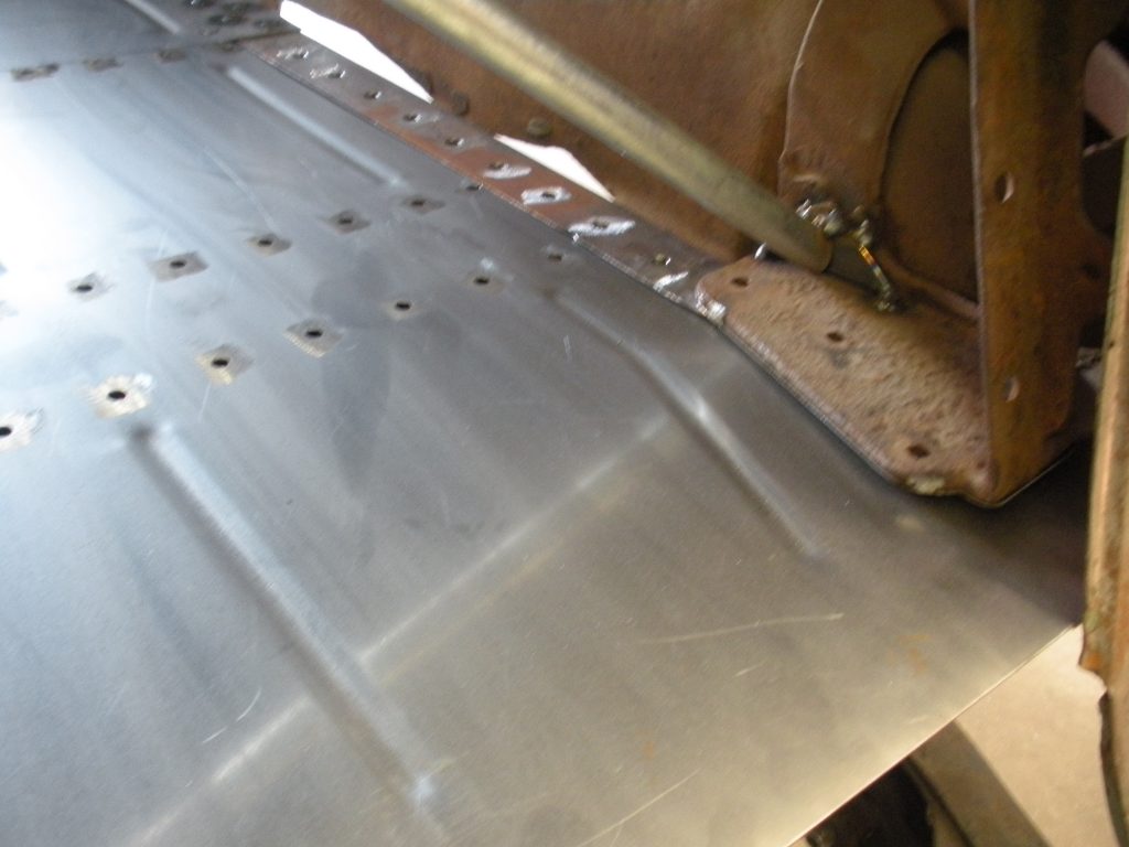 A metal sheet with holes in it is being worked on.