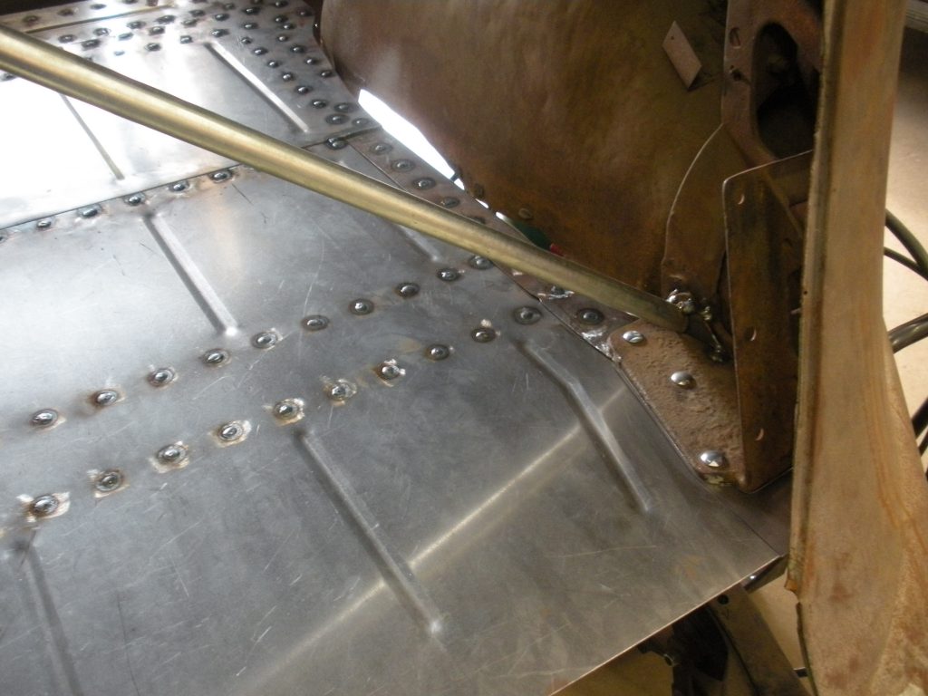 A metal sheet with rivets and holes on it.
