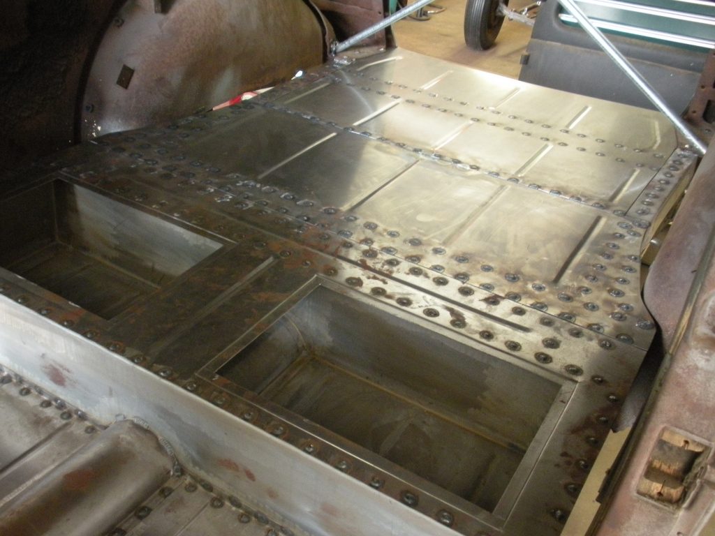 A metal table with holes in it and a person working on the top.