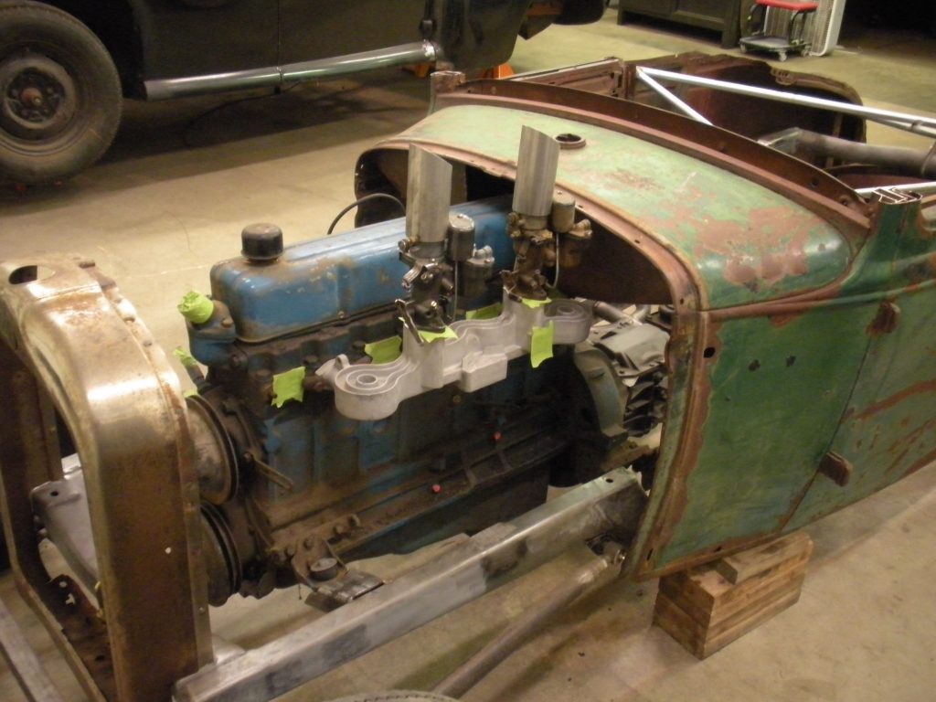 A green and blue car engine sitting in the middle of a room.