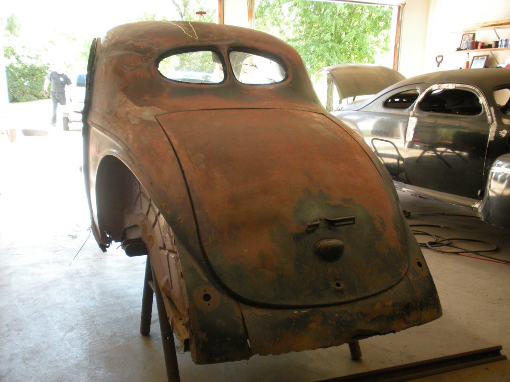 A rusty old car is being worked on.