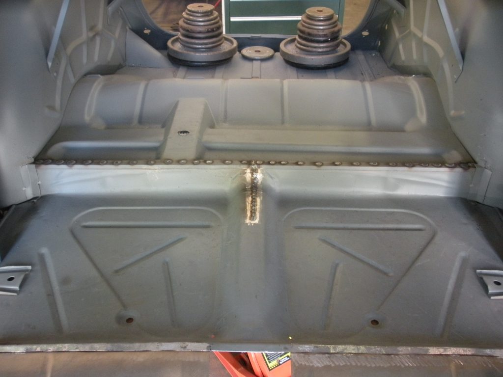 A car trunk with the door open and some parts missing.