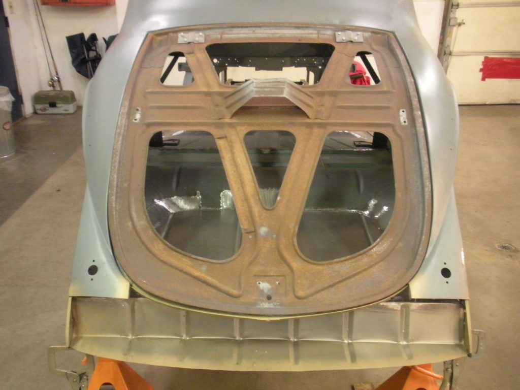 A car with the hood up and its rear end exposed.