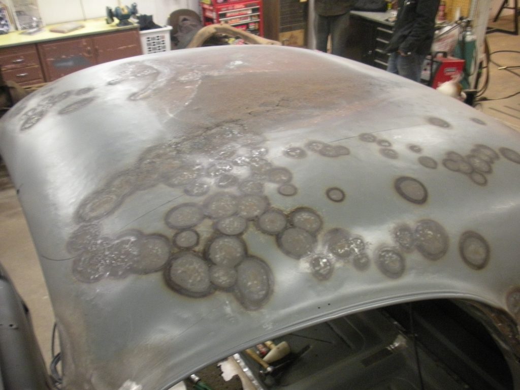 A car hood with some brown spots on it