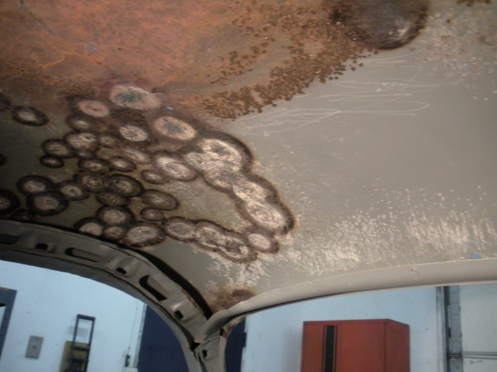 A ceiling with brown and white spots on it.