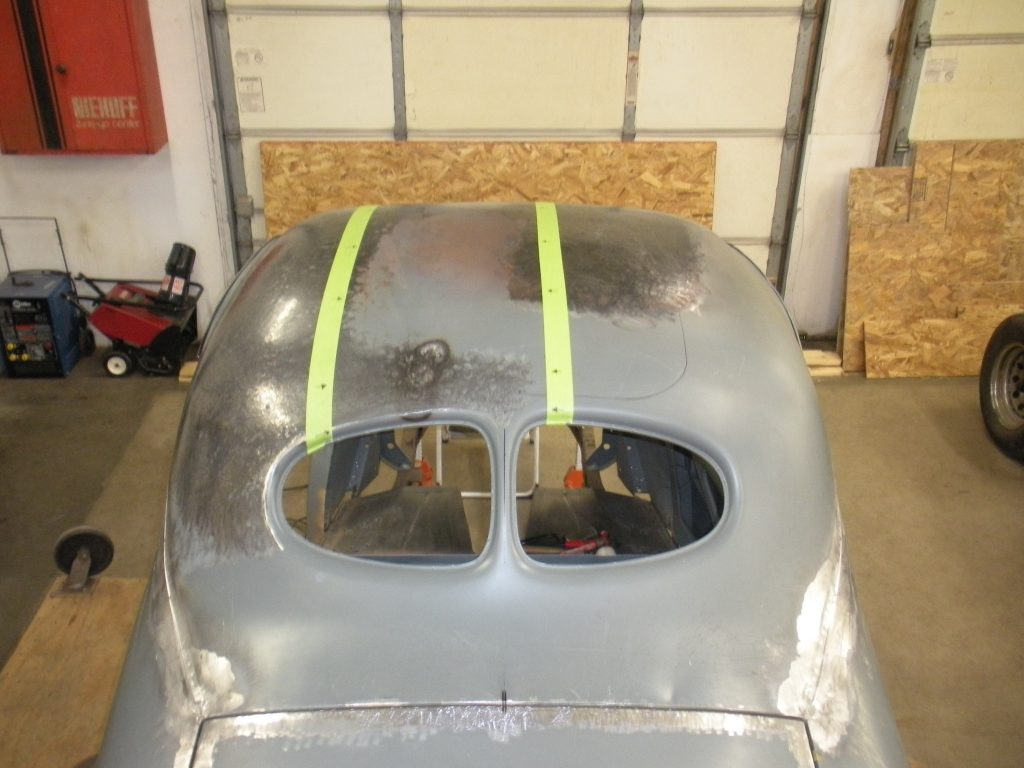 A silver car with yellow stripes on the hood.