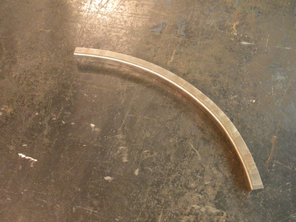 A bent piece of wood sitting on top of the floor.