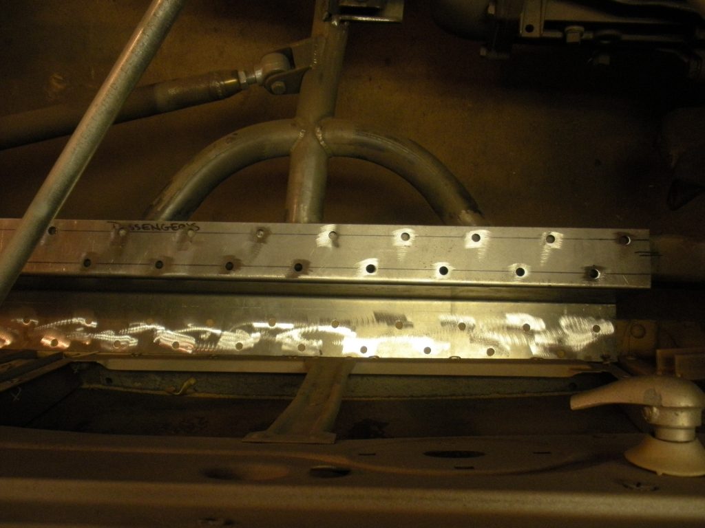 A metal bar with holes in it next to a pipe.