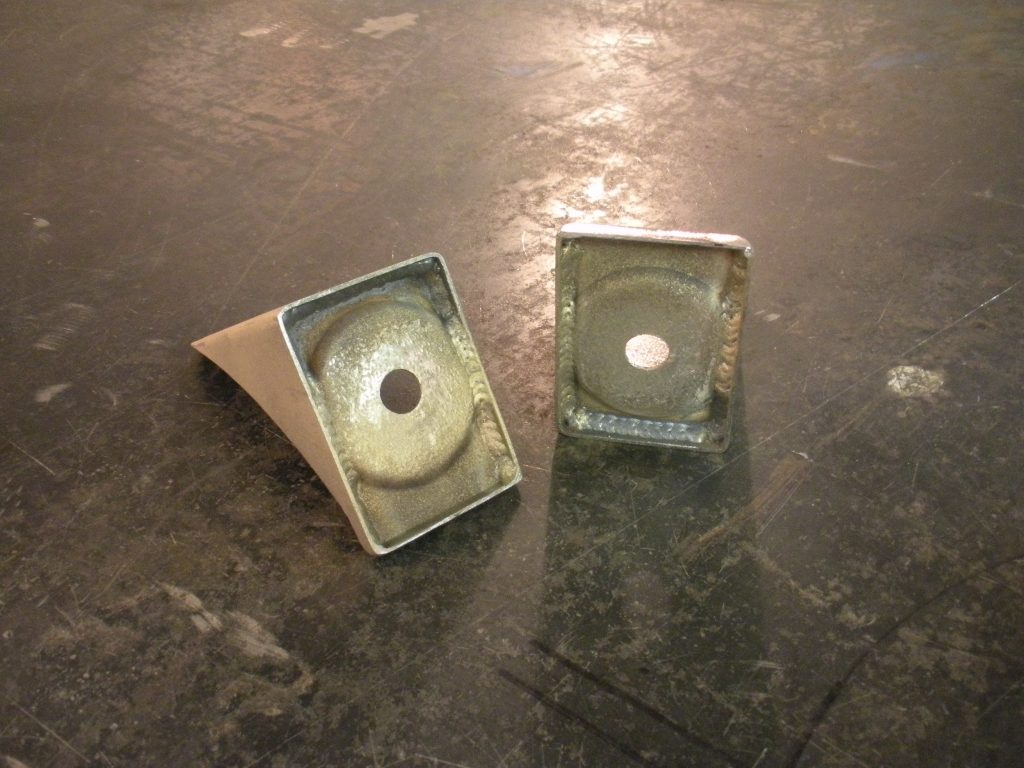 Two square metal objects sitting on a floor.