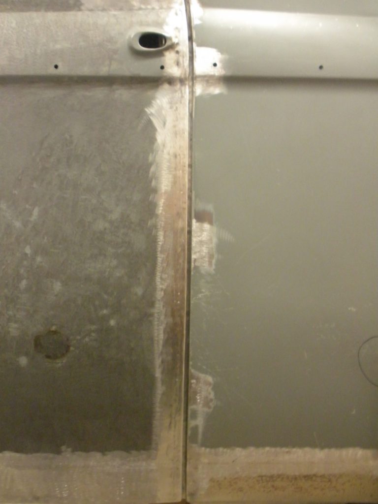 A bathroom wall with peeling paint and a metal frame.