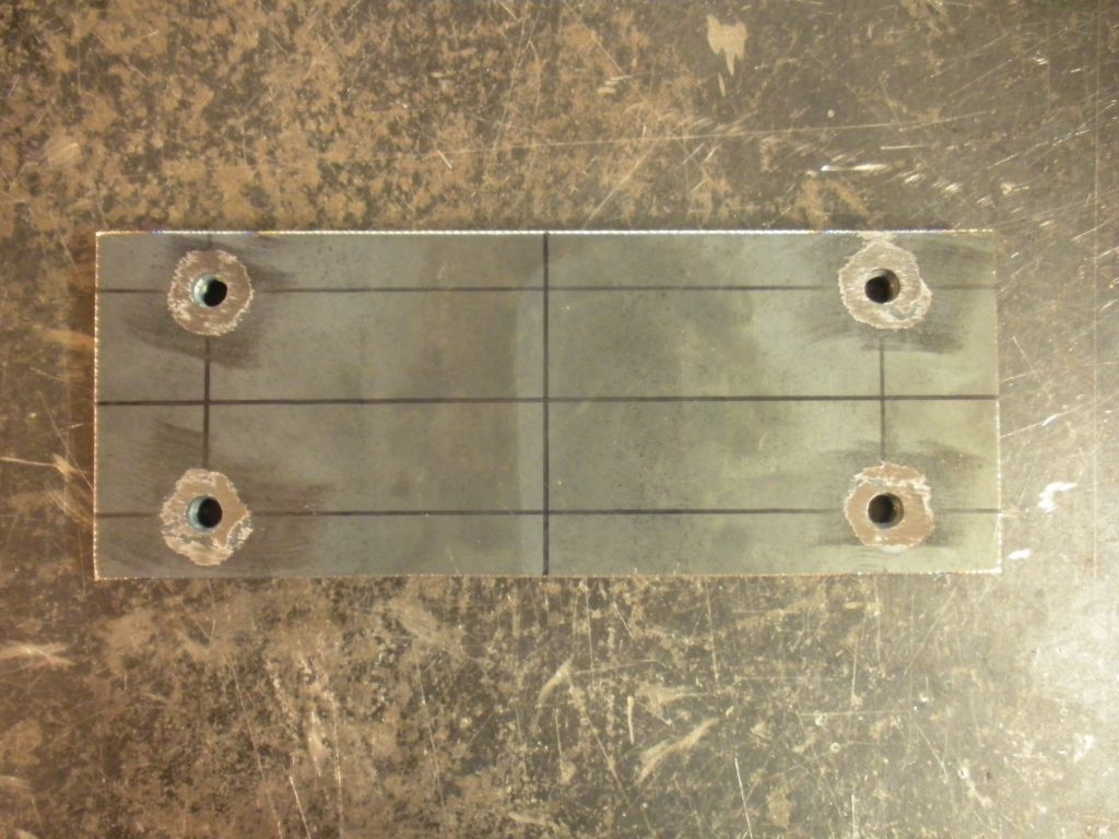 A metal plate with four holes on it.