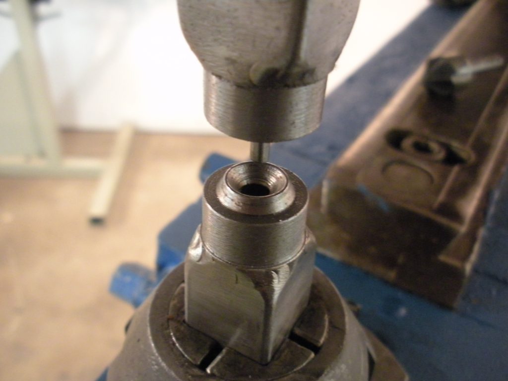 A drill press with a metal handle and some nuts