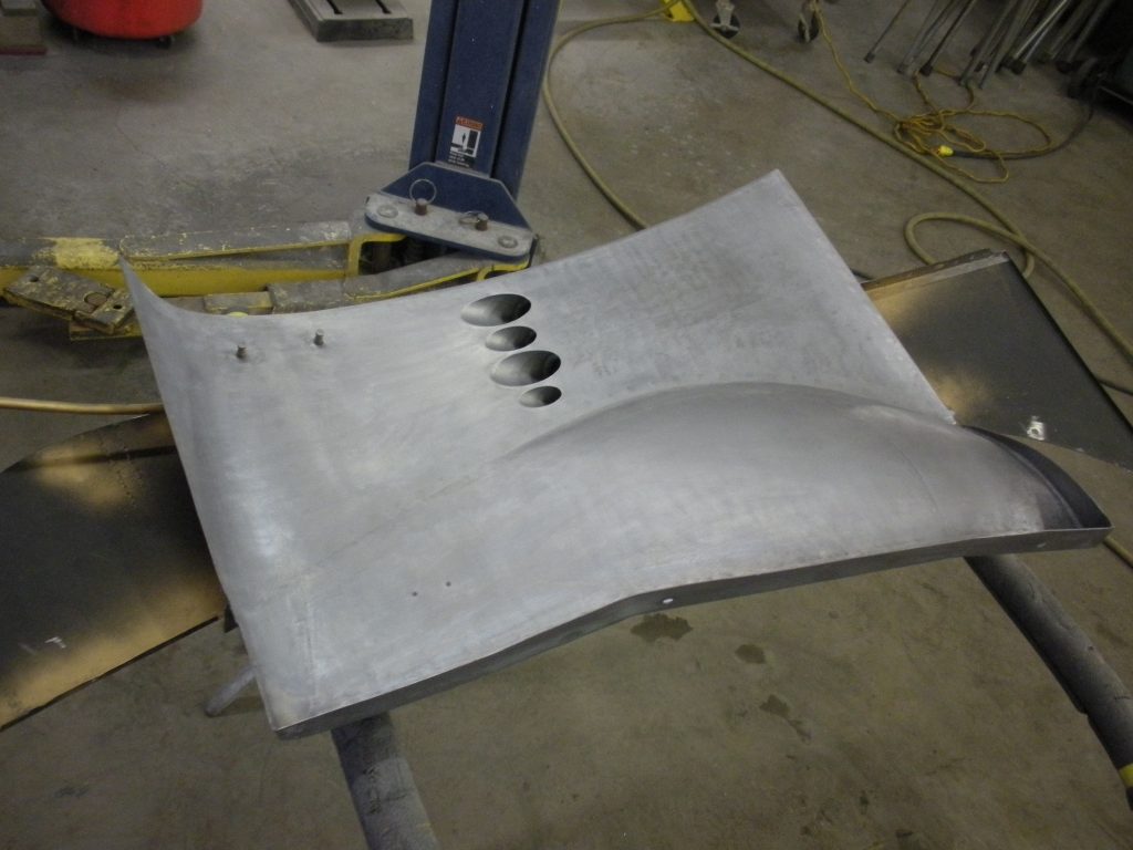 Metal car body panel, holes drilled.