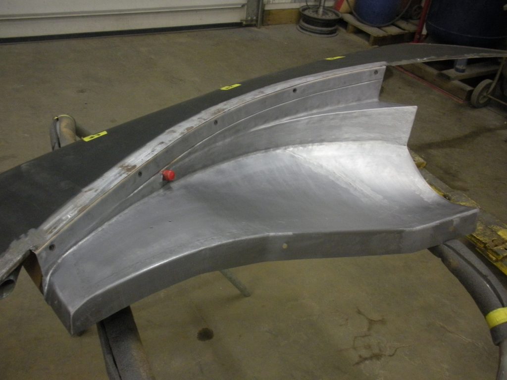 Here's an alt tag for the image: Metal car part under construction.
