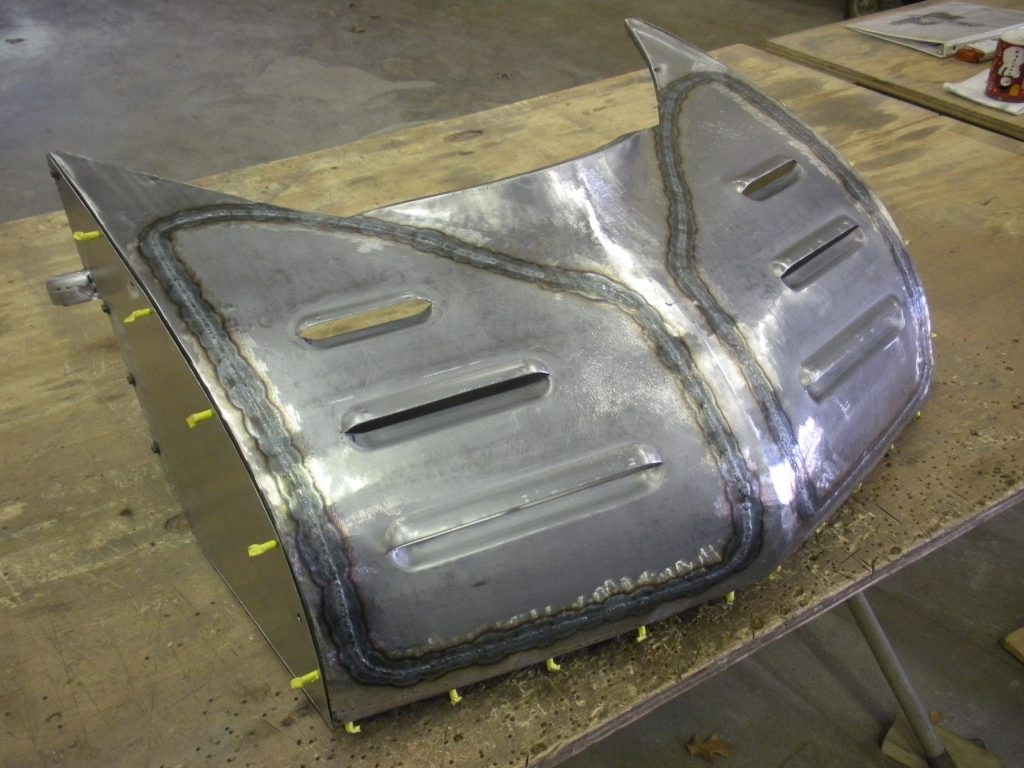 Welded metal car part with vents.