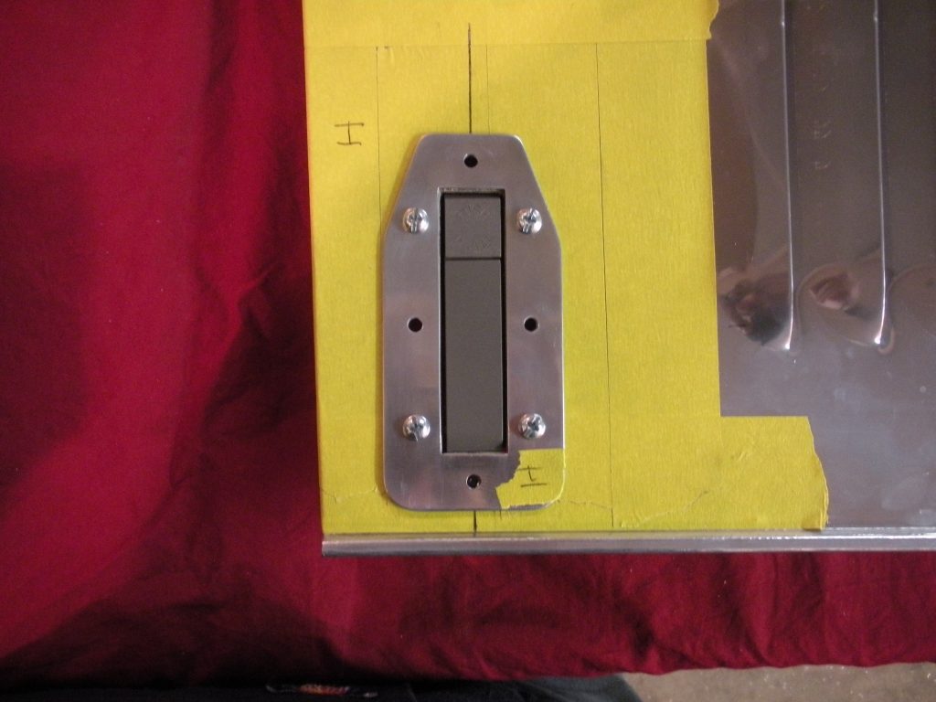 A metal door handle on the side of a yellow wall.