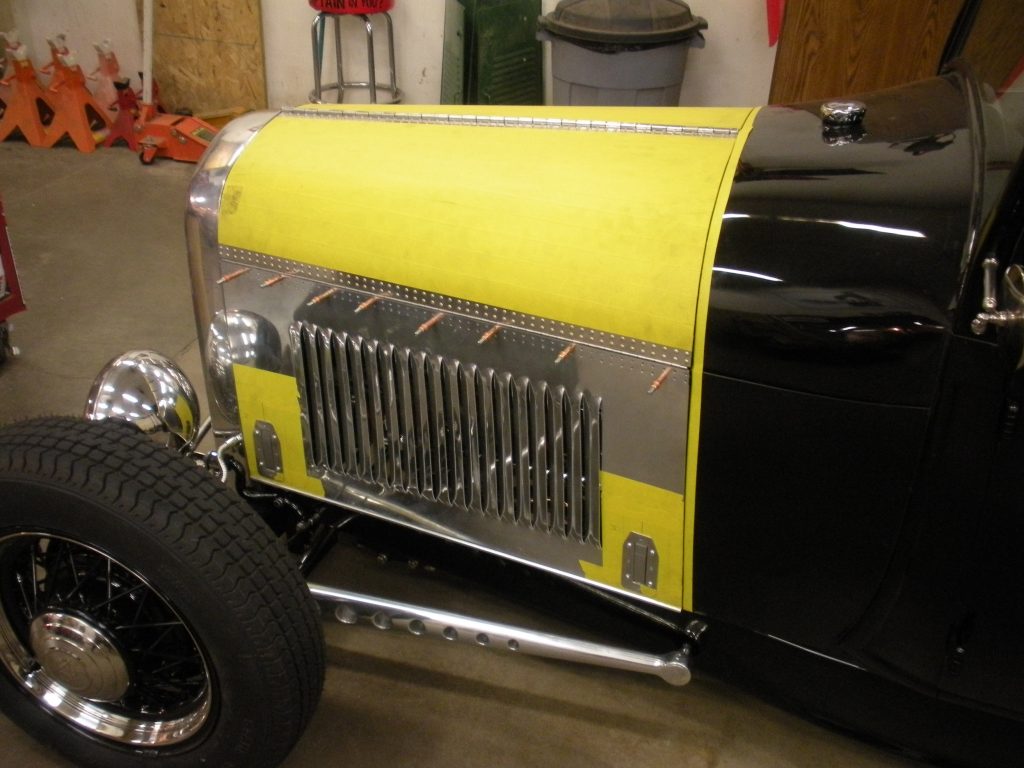 A black and yellow car with a grill on it's hood.