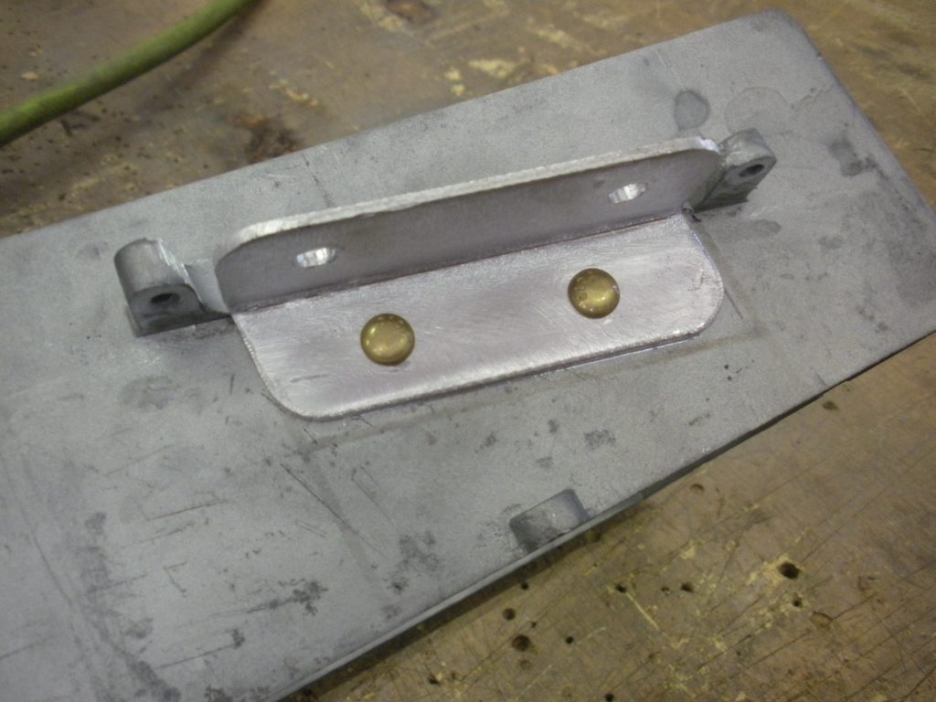 Close-up of metal bracket with brass pins.