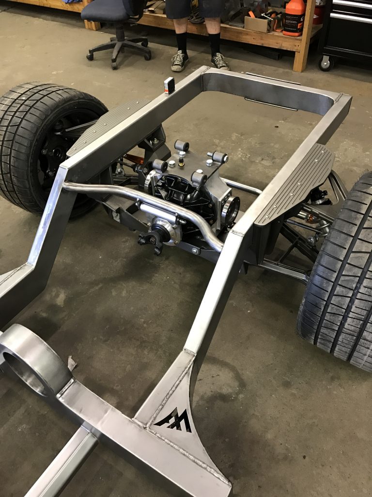 A car frame with wheels and tires on the floor