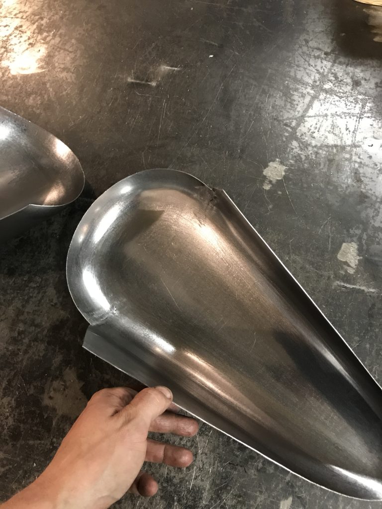 Hand holding a metal motorcycle part.