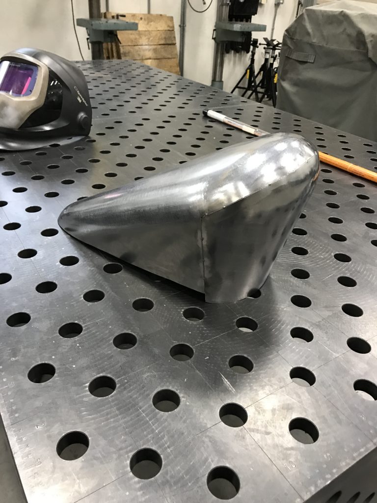 Metal part on perforated worktable.