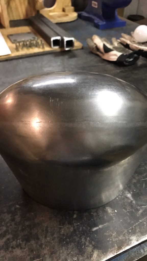 Metal dome-shaped workpiece on table.