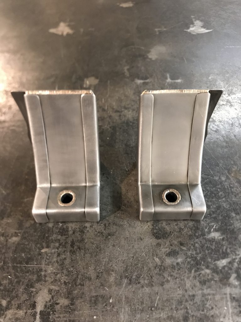 A pair of metal brackets sitting on top of a floor.